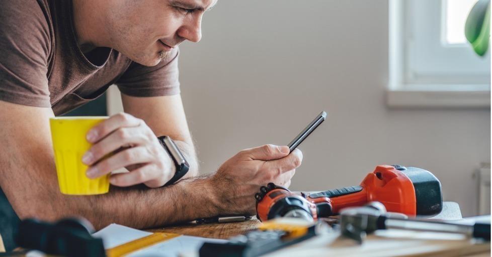 Man_using_phone_while_fixing_something